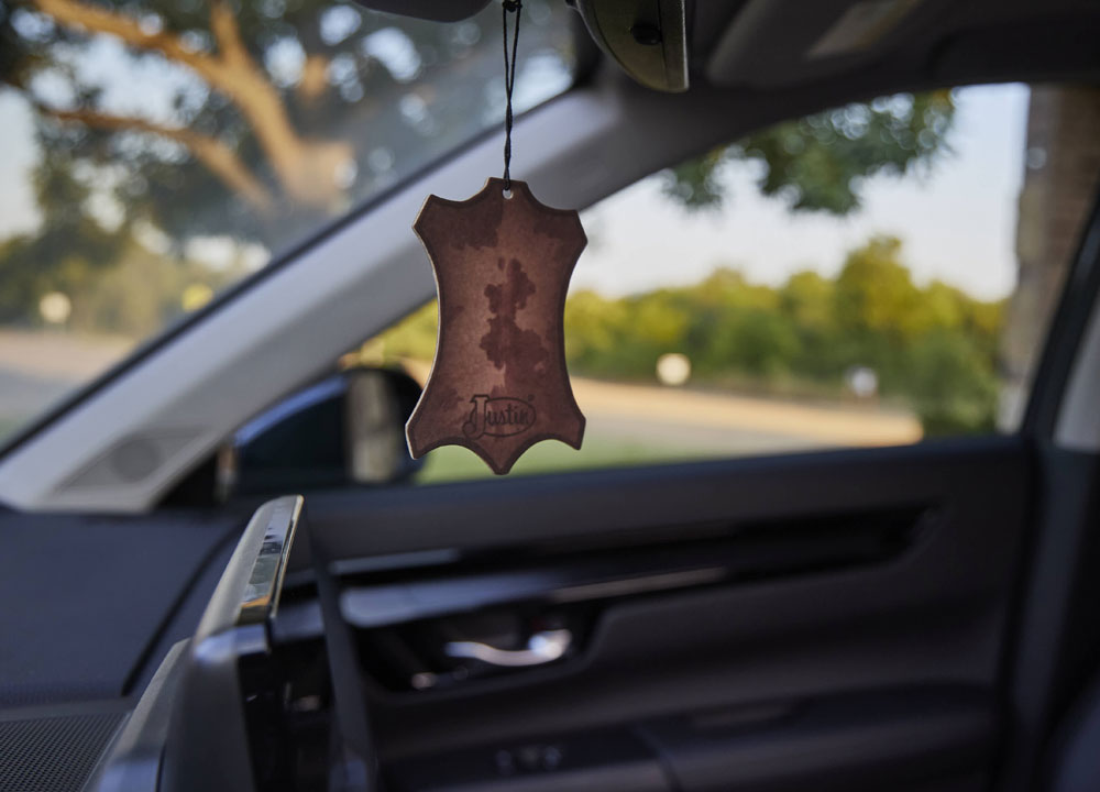 A Justin Air Freshener hanging from a car mirror.